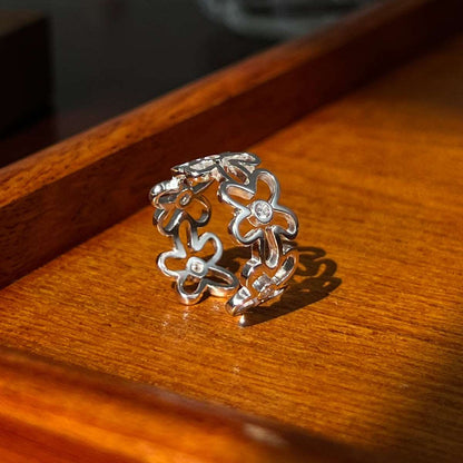  Angled view of the Adjustable Silver Flower Ring showcasing its elegant floral texture and the sparkling 5A cubic zirconia stones.