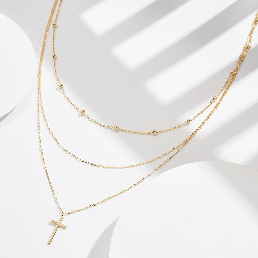 Triple layered silver necklace with cross pendant in two colors.