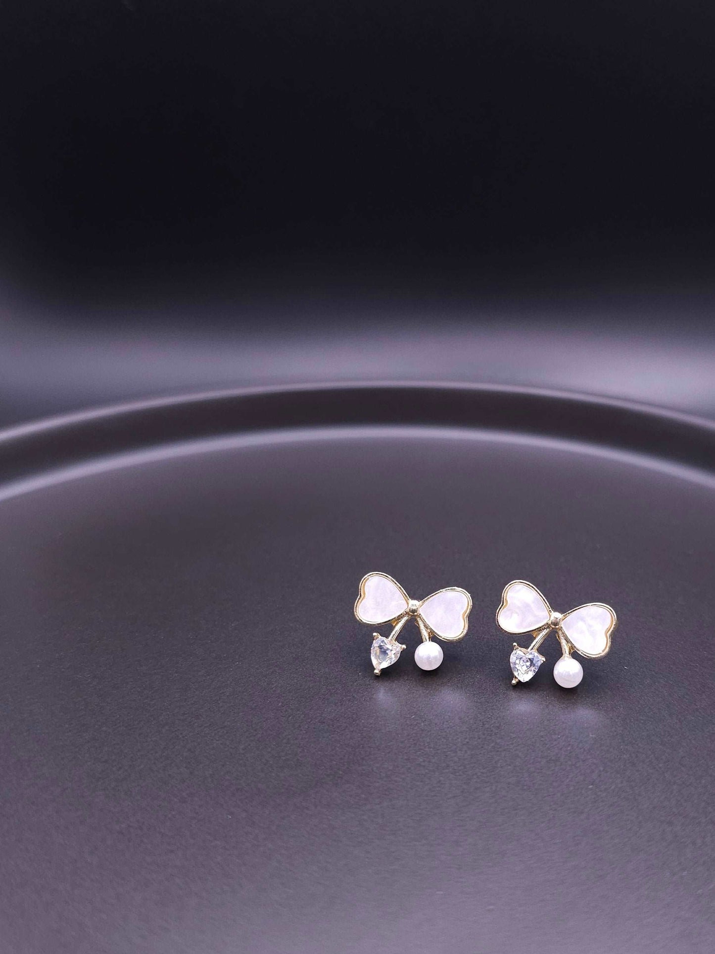 Elegant front view of bow stud earrings with sterling silver post, featuring pearl and crystal accents.