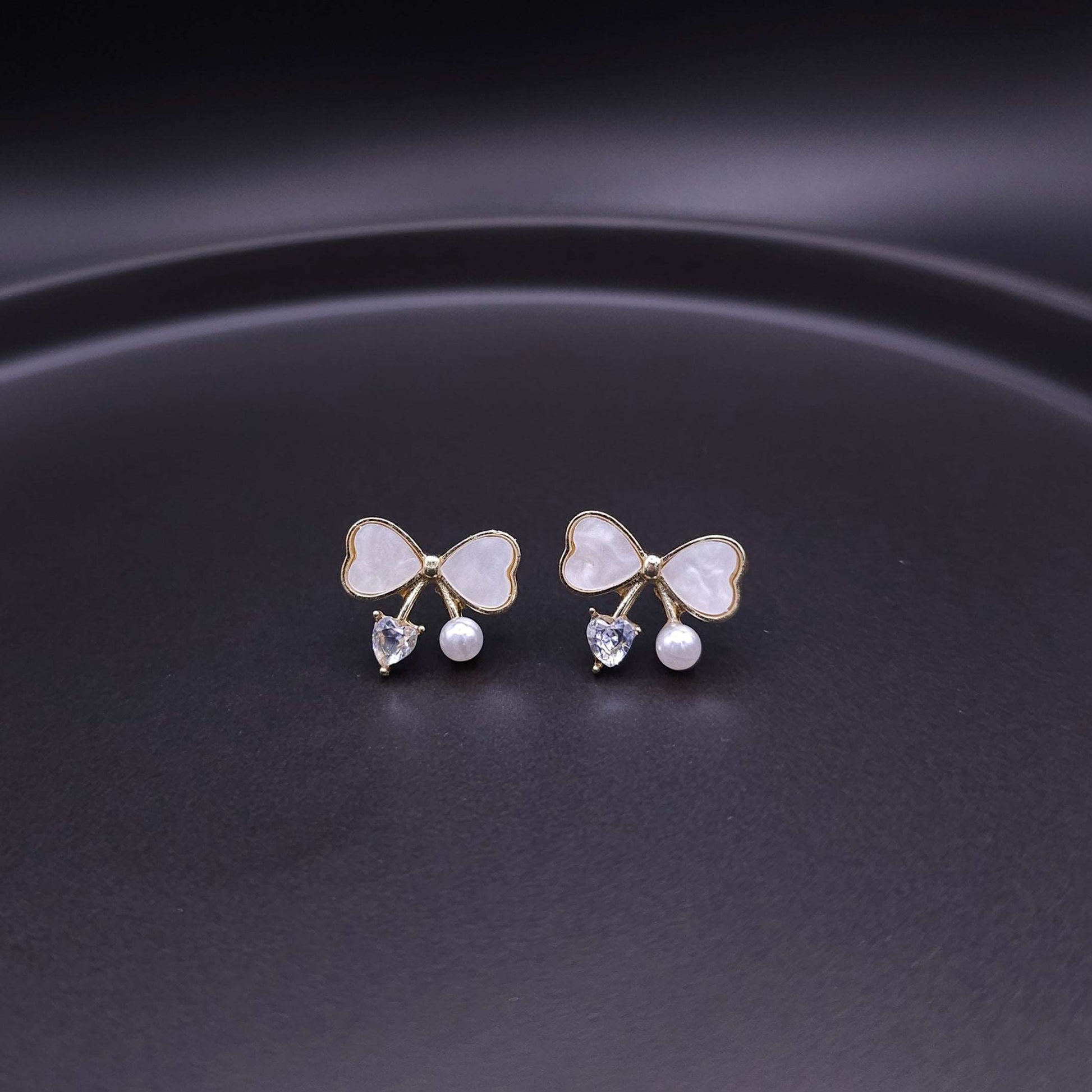 Front view of cute bow stud earrings with sterling silver post, adorned with elegant pearl and crystal points.