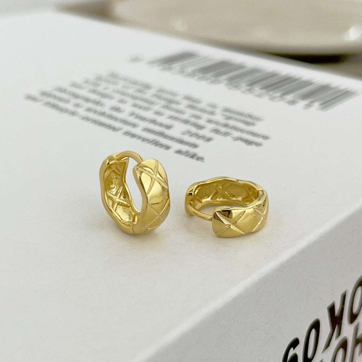 Side angle view of gold Embossing Huggie Earrings, showcasing their modern design and radiant gold finish.