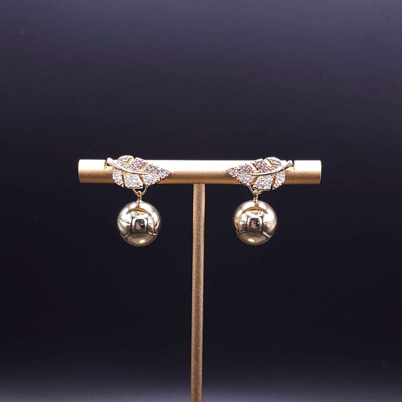 Front view of the Gold Leaf Earrings, emphasizing the sparkling cubic zirconia embedded in a delicate leaf design topped with a gold ball.