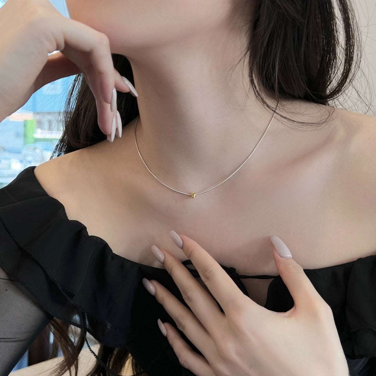 A close-up model shot of the Gold Point Necklace, showcasing how the gold ball pendant enhances the elegance of the outfit.