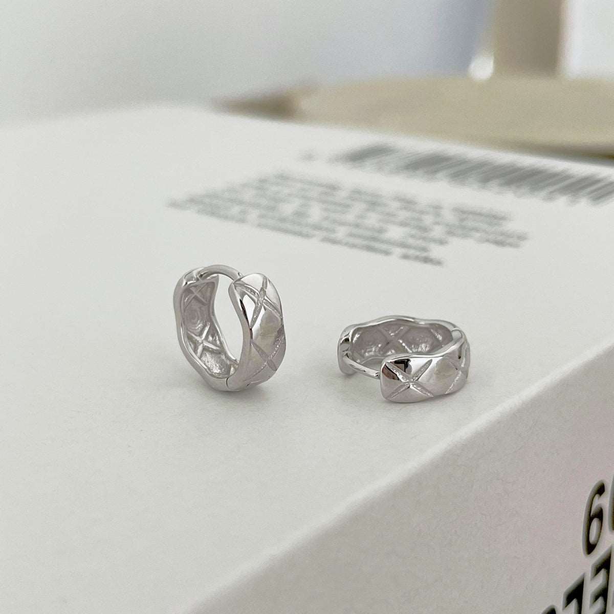 Side angle view of silver Embossing Huggie Earrings, highlighting the elegant design and luxurious rhodium finish.