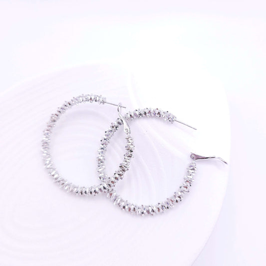 Bold silver hoop earrings with unique sparkling texture.