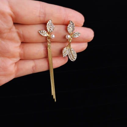 Close-up front view of Sparkling Leaf Whispers Earrings highlighting sparkling leaves and pearl details on a black background.